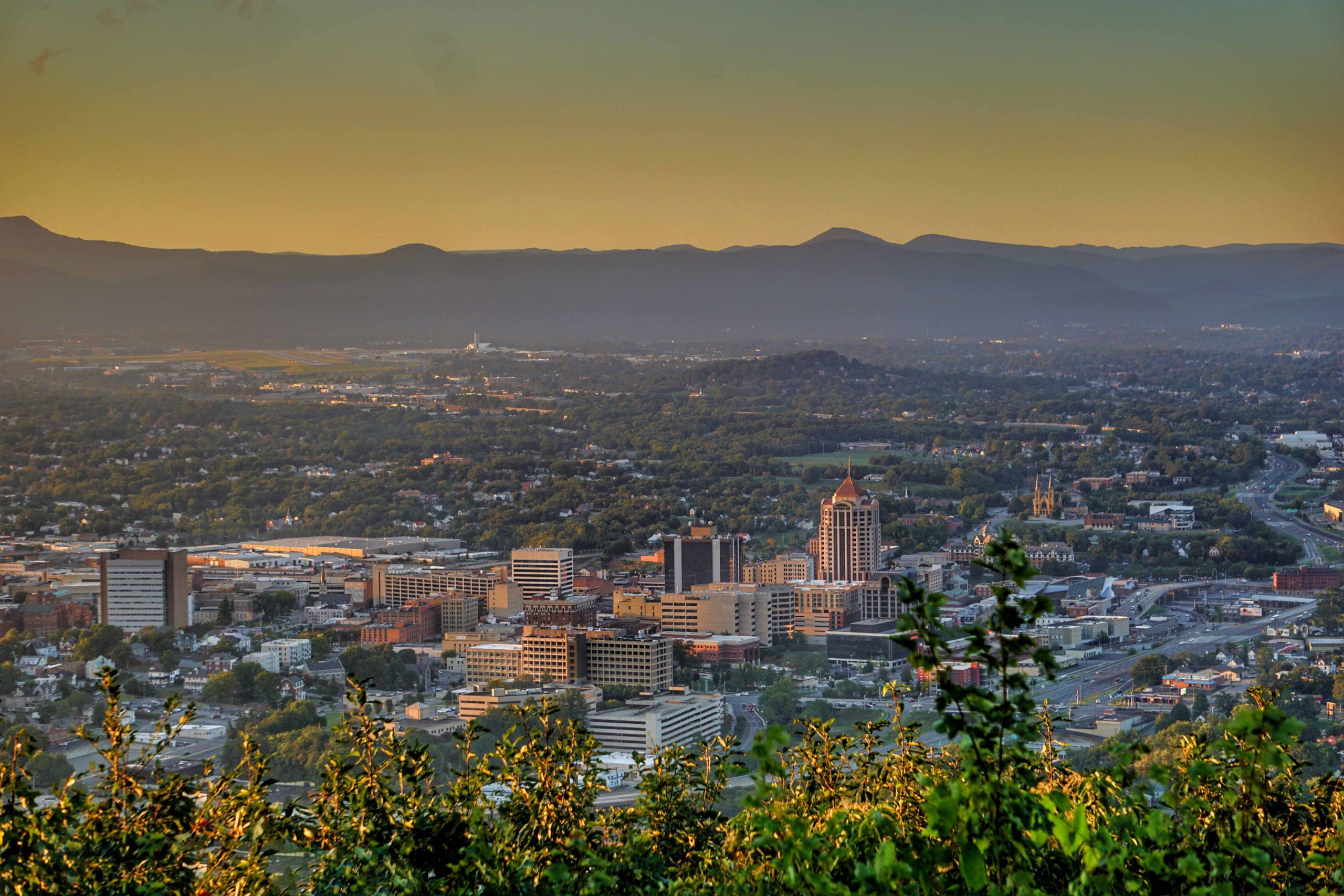 Sunset skyline view of a bustling city with mountains.