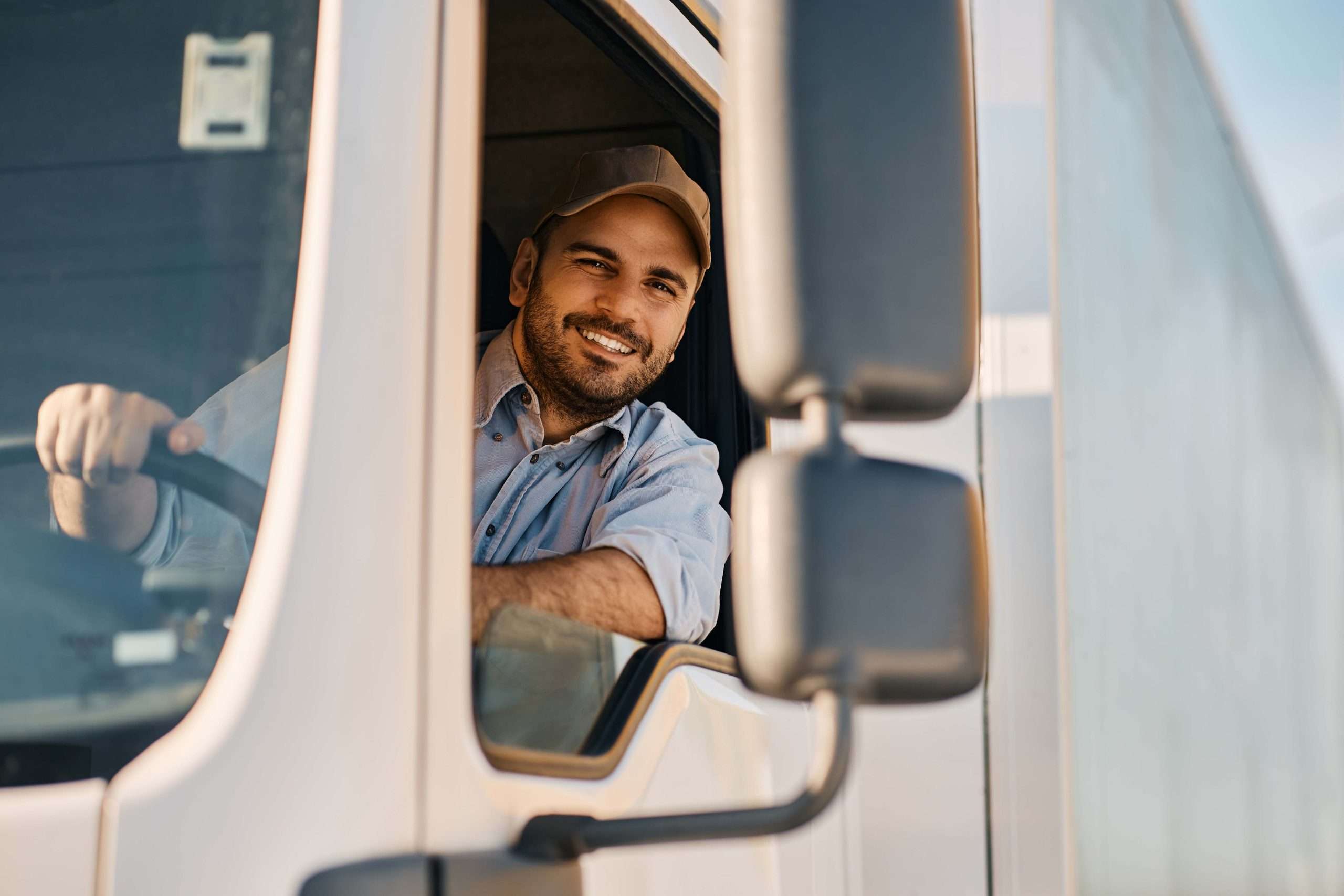Smiling truck driver inside vehicle cabin.